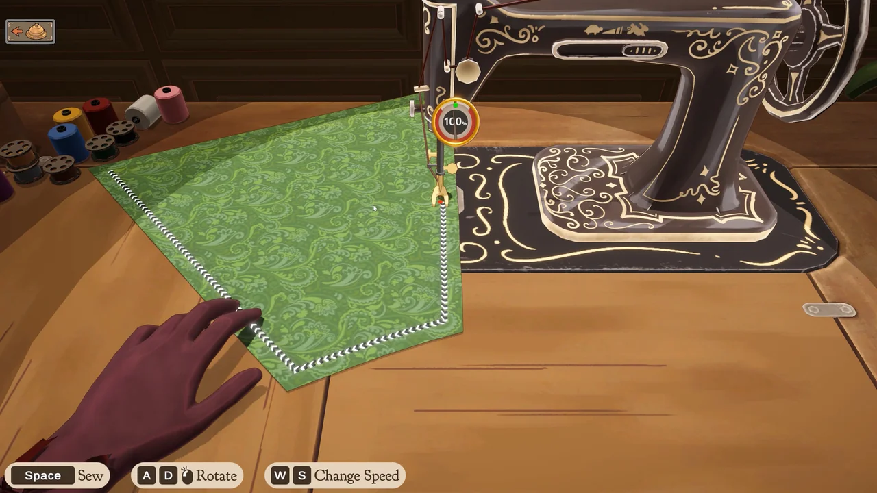 Official Dressmaker game screenshot showing the sewing machine and green fabric in the studio